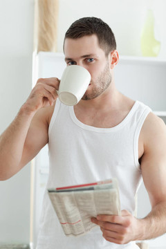 一個(gè)英俊的男子喝茶一邊看新聞的肖像