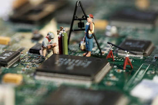 修復電子電路。一個微型雕像焊工在工作在電路板上；宏觀。