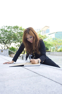 年輕漂亮的女人在樓梯上寫一本書