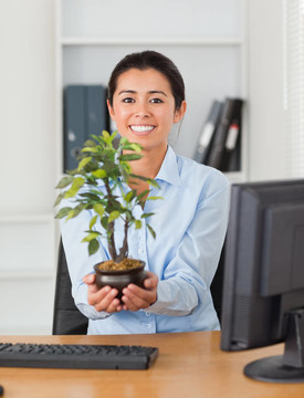 美女拿著植物一邊看著相機