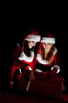 兩位女性在Santa服裝店開啟圣誕禮物。
