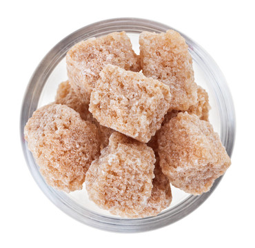 布朗塊蔗糖在一個(gè)玻璃碗；孤立的白色