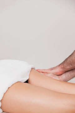 女人按摩她的大腿的按摩師