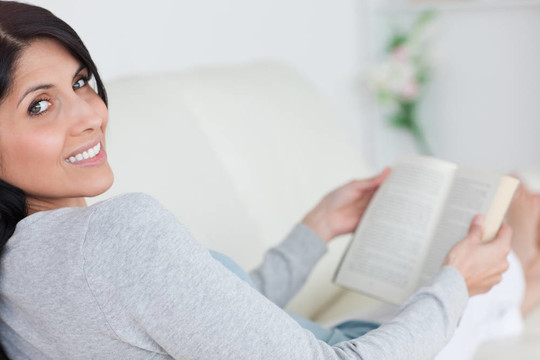 女人躺在沙發(fā)上拿著一本書