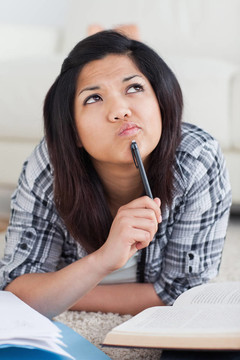 思考的女人躺在地板上，手里拿著一支鋼筆