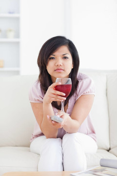 女人坐在沙發(fā)上，手里拿著一杯紅酒
