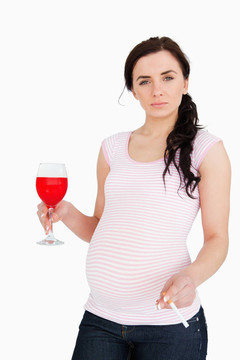 懷孕的年輕婦女拿著酒精飲料和香煙