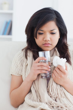 生病的女人拿著一杯水