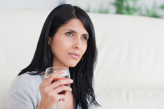 女人拿著一杯滿是酒的酒杯
