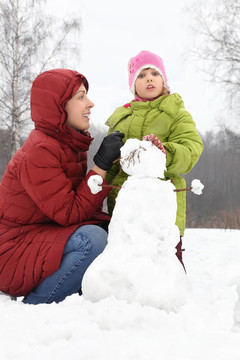冬天，媽媽和女兒一起蹲在雪人街上