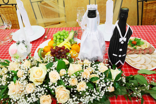 裝著結(jié)婚禮服的香檳酒放在節(jié)日餐桌上，上面擺滿(mǎn)了食物和鮮花