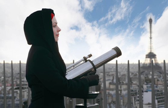 站在凯旋门上的年轻女子用一双大望远镜；埃菲尔铁塔