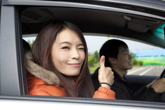 幸福微笑的情侶在車上開著大拇指