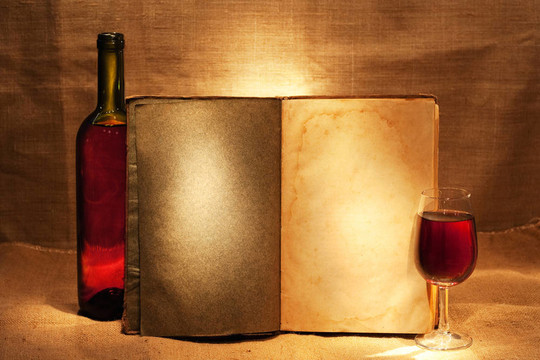 酒與開放的書在溫暖的黃昏光