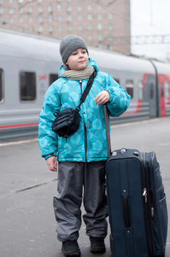 一個(gè)男孩帶著一個(gè)旅行包在火車附近