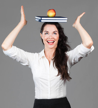 女人平衡苹果和书籍的头