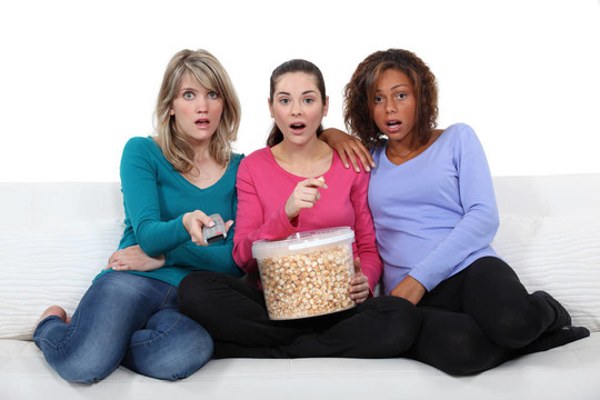 三个朋友看电视和吃爆米花