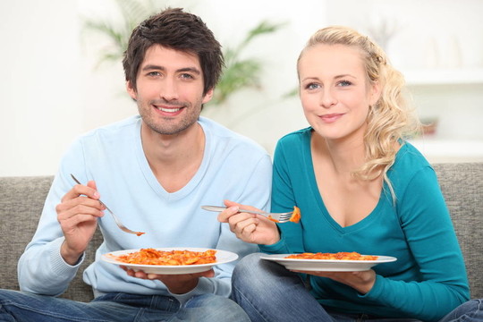 在沙發(fā)上吃晚飯的夫婦