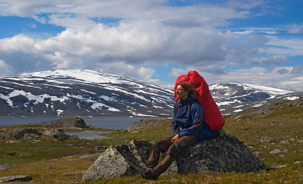 年輕人靠在巖石和欣賞美麗的景觀在挪威北部沿nordkalottleden
