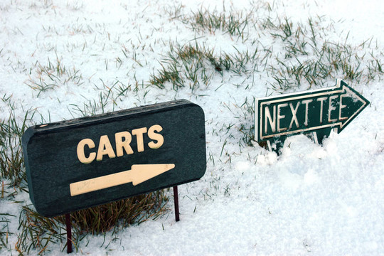 在冰雪覆蓋的高爾夫球場上的推車和下發(fā)球標志