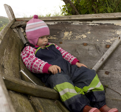 无聊和烦恼的孩子（3岁）坐在旧船上。