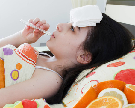 帶溫度計的年輕女孩在床上