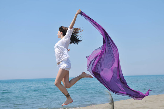 美麗的年輕女子在海灘與圍巾
