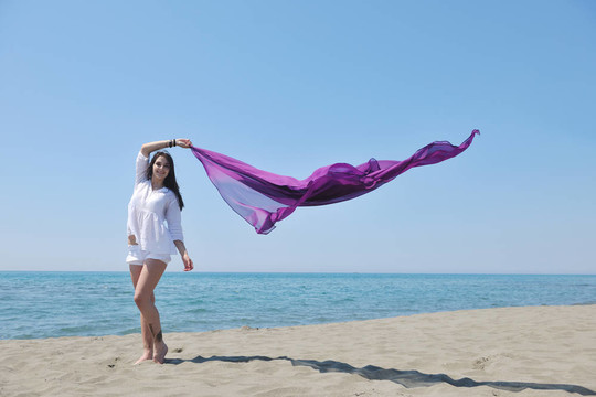 美麗的年輕女子在海灘與圍巾