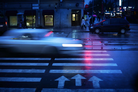 汽車在夜間穿越人行橫道；運動模糊。