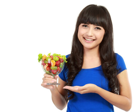 一個年輕漂亮的女人在孤立的背景吃水果沙拉特寫肖像