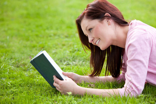 聰明的女人躺在草地上看書