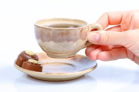 果仁巧克力；杯；黑咖啡和女性手上白色
