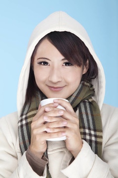 年輕的女人穿著冬天的衣服，端著咖啡杯
