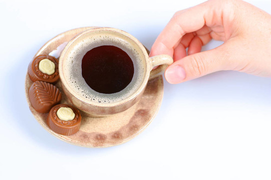 果仁巧克力；杯；黑咖啡和女性手上白色