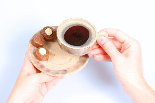 果仁巧克力；杯；黑咖啡和女性手上白色