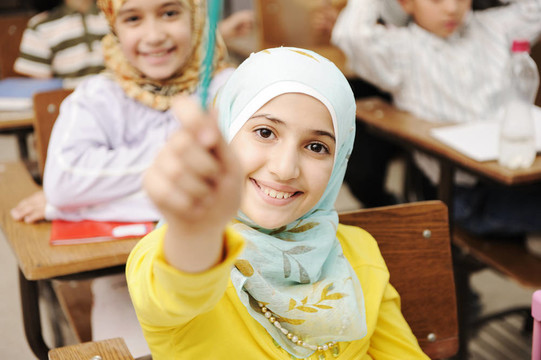 可爱的穆斯林女孩在教室里和她的朋友孩子们在一起