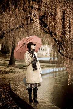 下雨天在公園里帶著雨傘和圍巾的女孩。照片與自然色彩的復(fù)古風(fēng)格。