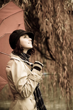 下雨天在公園里帶著雨傘和圍巾的女孩。照片與自然色彩的復(fù)古風(fēng)格。