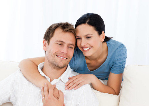 可愛(ài)的女人擁抱她的男友在沙發(fā)上放松