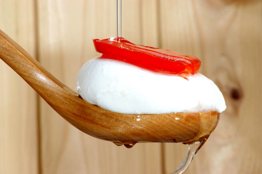 在一個(gè)木勺子，一片番茄和油Mozzarella