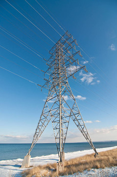 冬季湖旁輸電線路高壓輸電鐵塔。