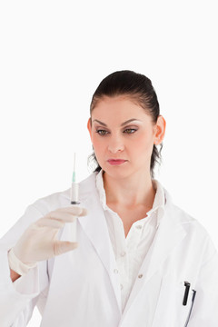 穿著白色上衣的女人在白色背景上準(zhǔn)備注射器