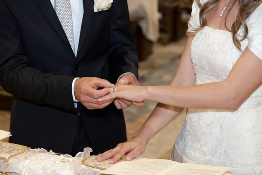 新郎把結(jié)婚戒指戴在新娘的手指上