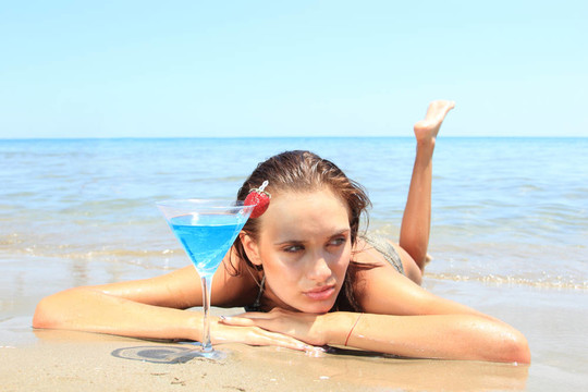海灘上的年輕女人伴著雞尾酒