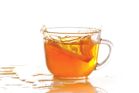 一杯冰茶和檸檬在白色背景上飛濺