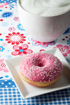 粉红色的甜甜圈和一杯卡布奇诺