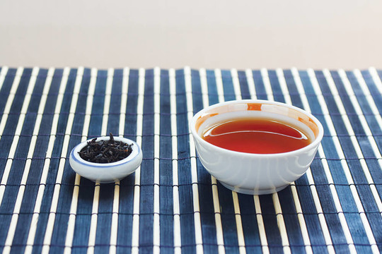 一杯茶和一罐茶葉在竹桌布上還活著