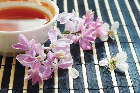 一杯茶和丁香花在竹桌布上的靜物