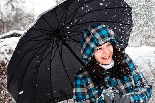 在暴風(fēng)雪中帶雨傘的年輕女子