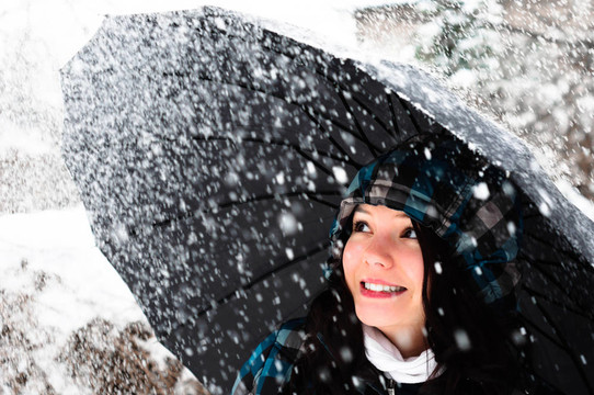 在暴風(fēng)雪中帶雨傘的年輕女子